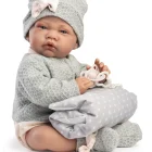 Muñeca Recién Nacida Lúa sentada con conjunto gris, sosteniendo el cojín de estrellas y el chupete entre las manos.
