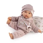 Muñeca Petit con Sudadera sentada sobre un cojín estampado, con gorro rosa y una pierna levantada.