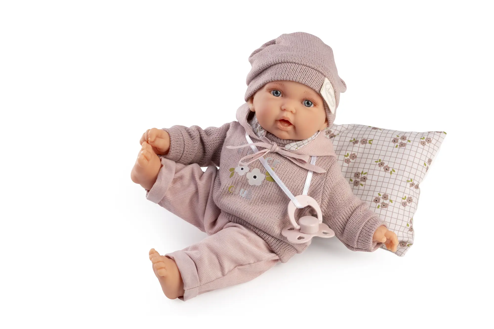 Muñeca Petit con Sudadera sentada sobre un cojín estampado, con gorro rosa y una pierna levantada.