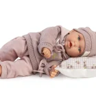 Muñeca Petit con Sudadera tumbada de lado sobre un cojín estampado, con gorro y conjunto rosa.