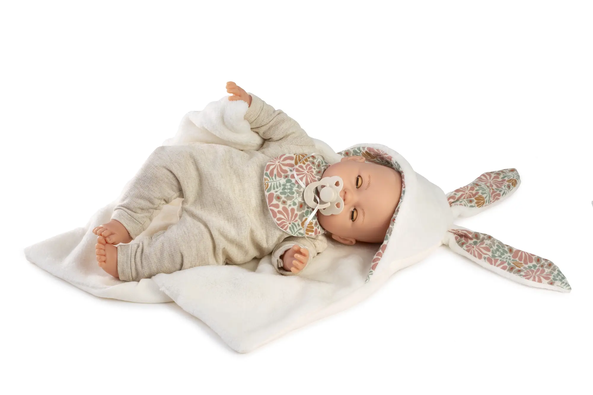 Muñeca Bimba Lloro Orejitas tumbada con chupete sobre una manta blanca con capucha de orejas y forro floral.