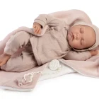 Muñeca Recién Nacida Luna de Antonio Juan dormida de lado sobre una toquilla rosa, con conjunto de punto y gorro con pompón.