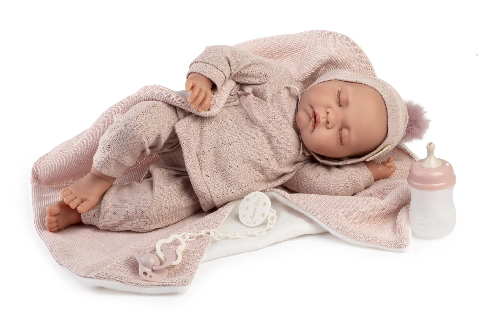 Recién Nacida Luna dormida con toquilla Muñeca Recién Nacida Luna de Antonio Juan dormida de lado sobre una toquilla rosa, con conjunto de punto y gorro con pompón.