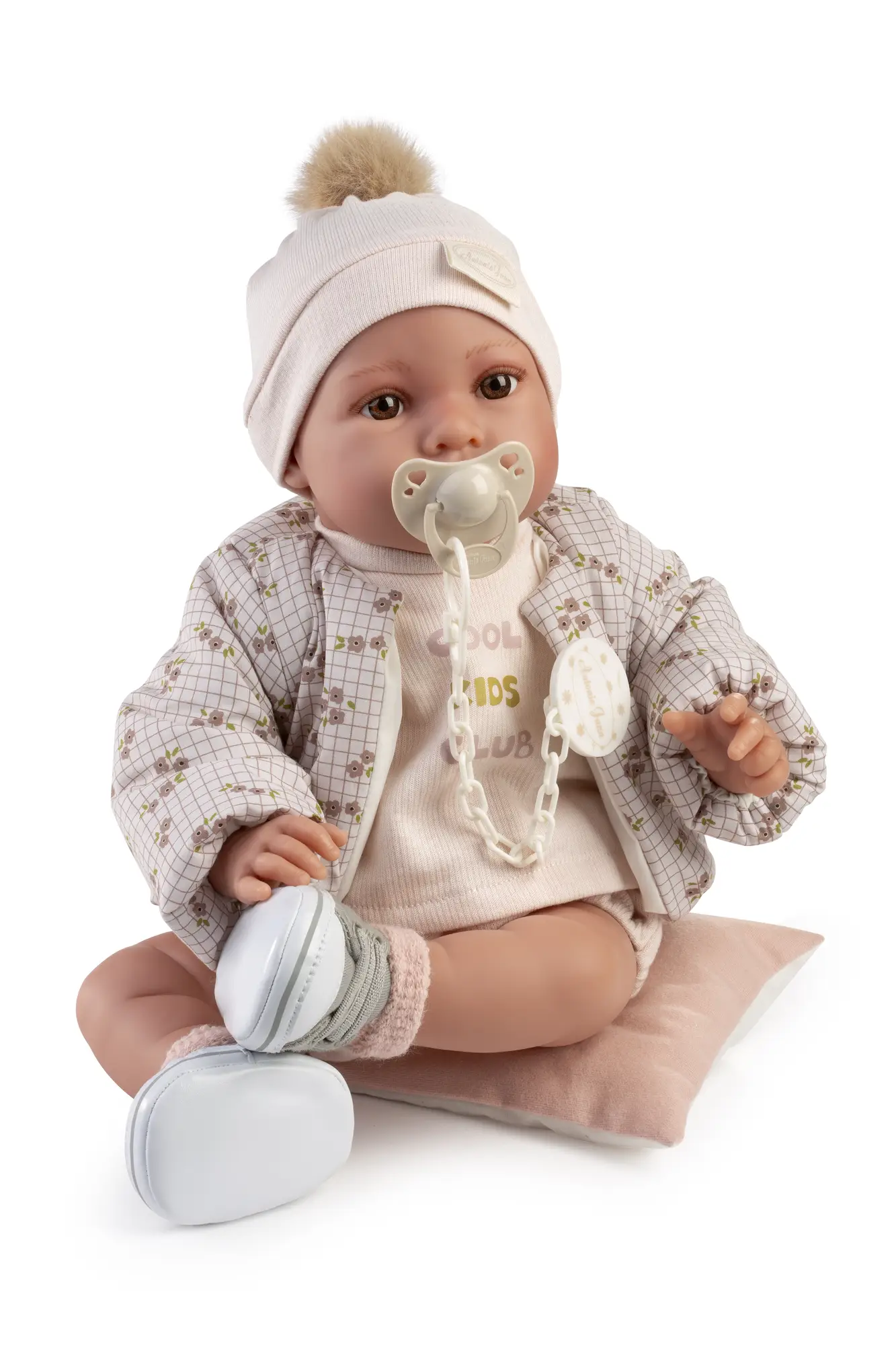 Recién Nacida Erika Bomber con chupete Primer plano de la muñeca Recién Nacida Erika Bomber con gorro de pompón, chaqueta estampada y chupete.