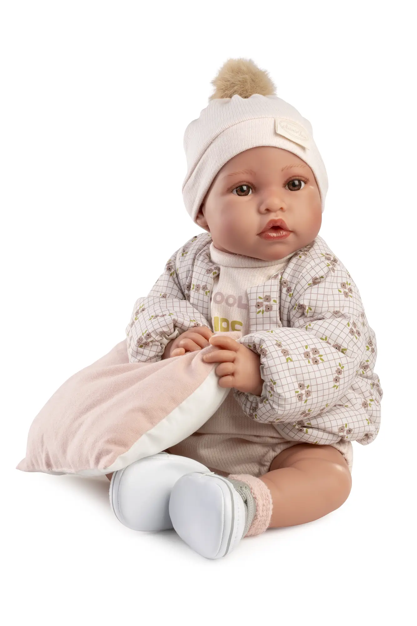 Primer plano de la muñeca Recién Nacida Erika Bomber con gorro de pompón y chaqueta de cuadros con flores.