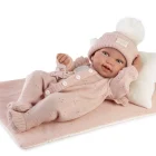 Muñeca Recién Nacida Pipa de Antonio Juan recostada sobre una colcha rosa, con conjunto de punto, gorro con pompón y cojín blanco.