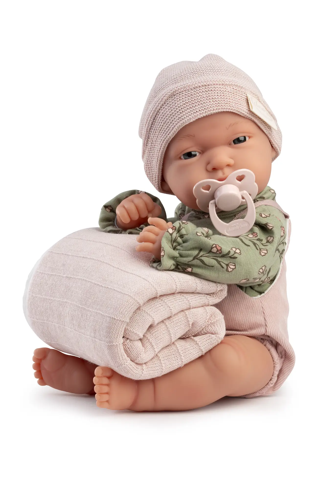 Baby Toneta Pana sentada con manta y chupete Muñeca Baby Toneta Pana sentada con gorro rosa, blusa verde de flores, chupete y una manta doblada en brazos.