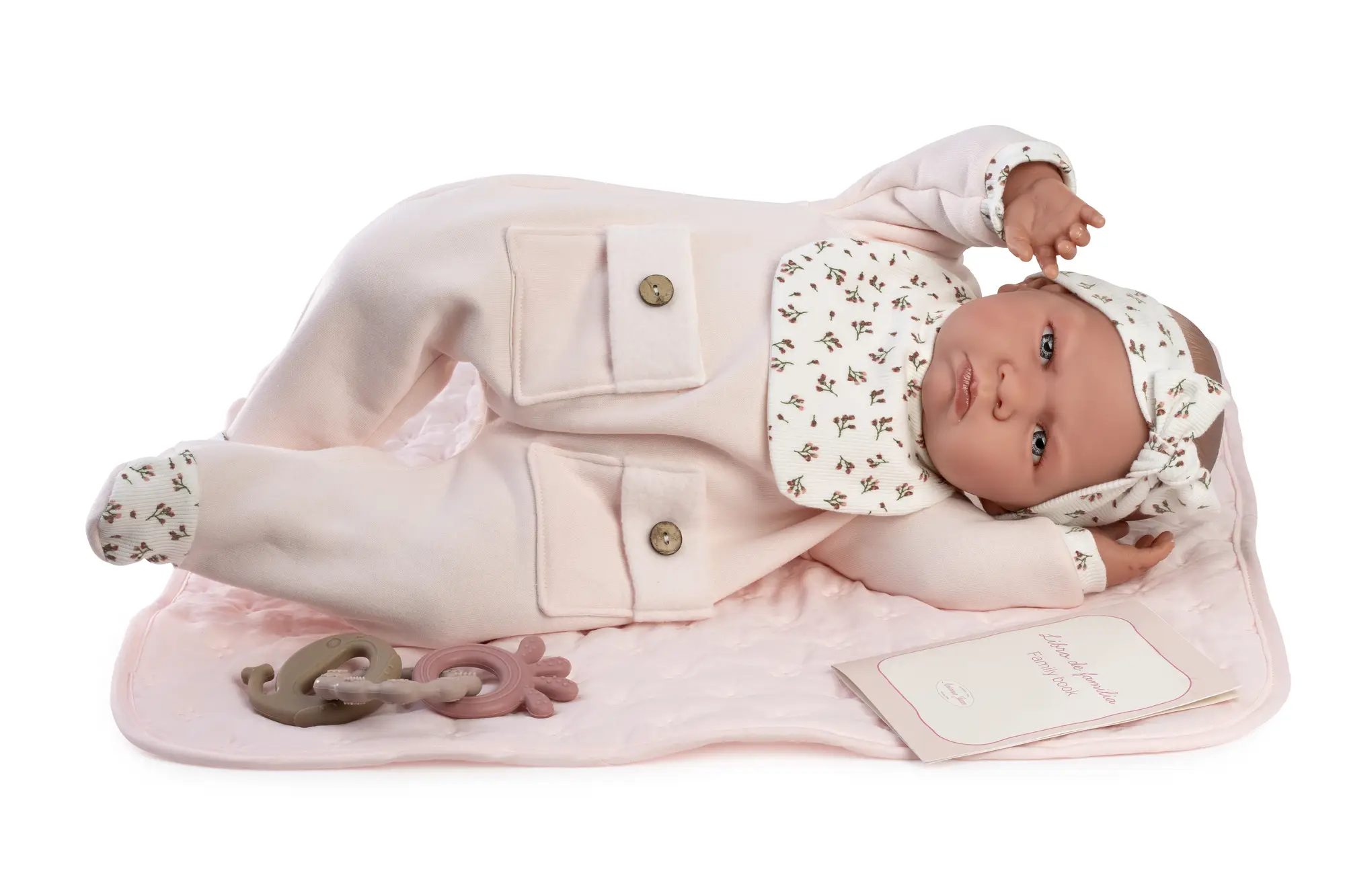 Muñeca Mi Primer Reborn Berta de Antonio Juan tumbada sobre una manta rosa, con lazo y conjunto de detalles florales.