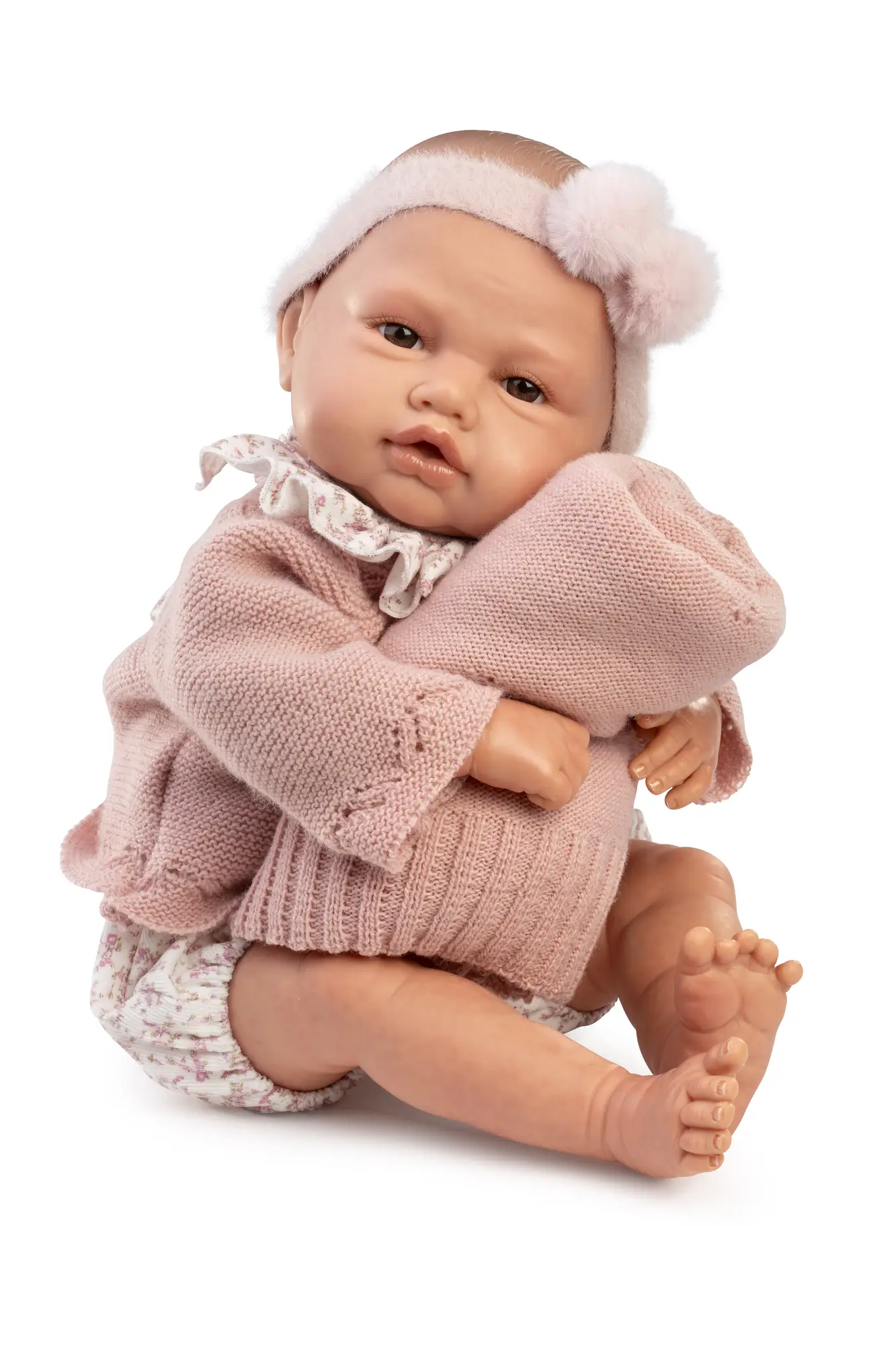 Muñeca Reborn Baby Love de Antonio Juan sentada y abrazando una manta de punto rosa.