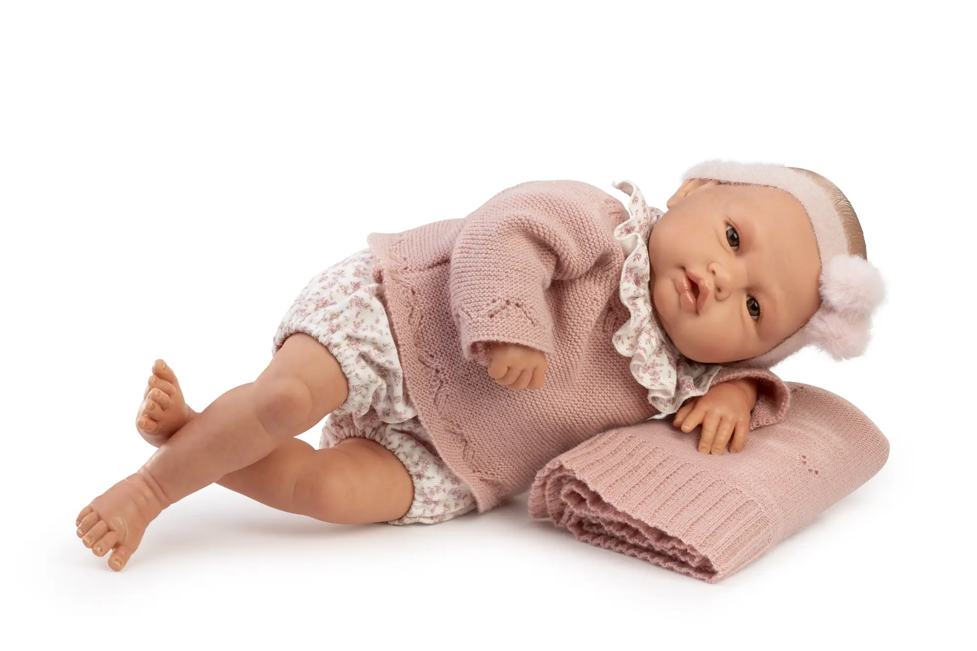 Muñeca Reborn Baby Love de Antonio Juan recostada de lado con la cabeza apoyada sobre una manta rosa doblada.