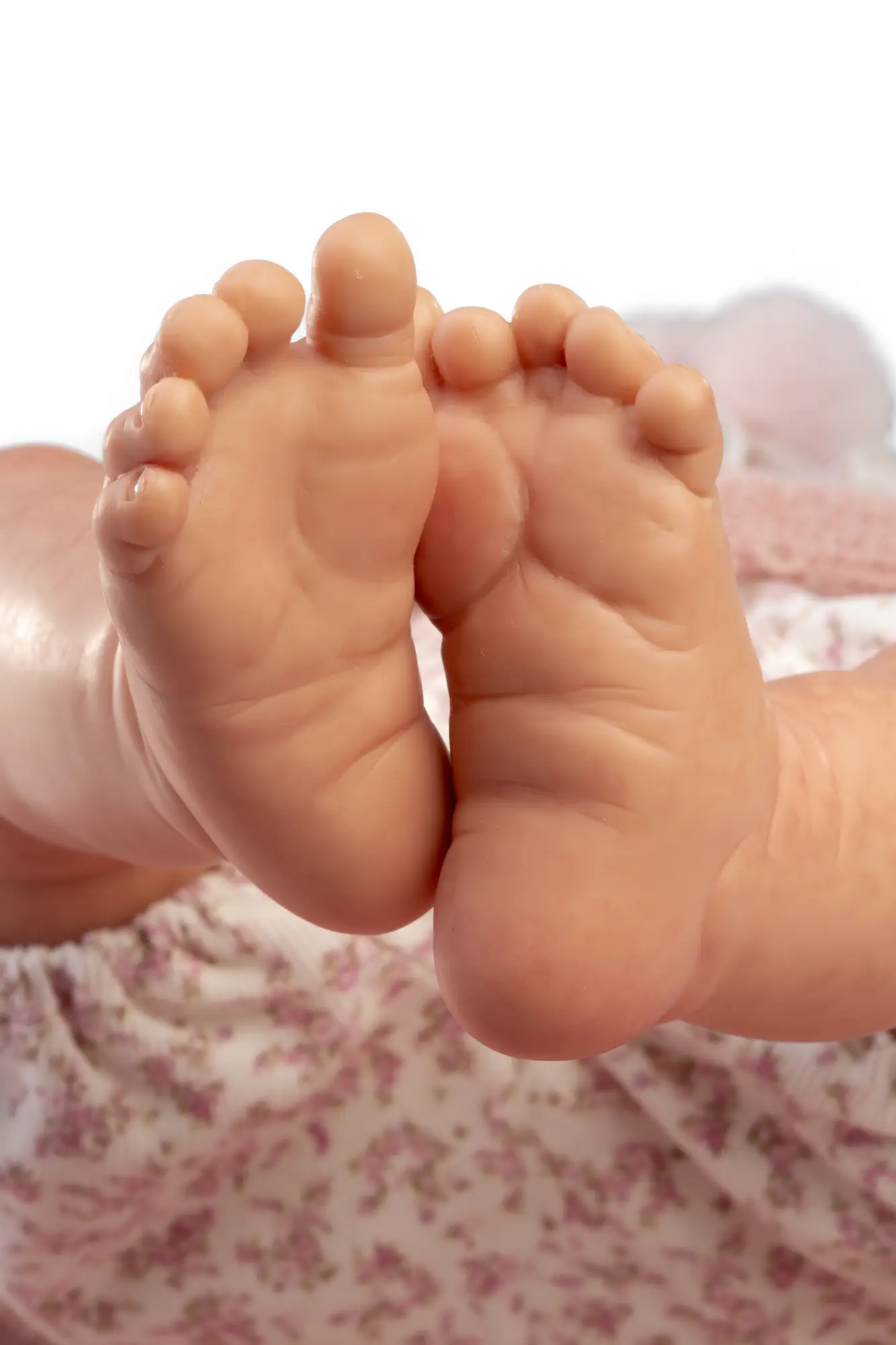 Primer plano de las plantas de los pies de la muñeca Reborn Baby Love sobre tela floral.