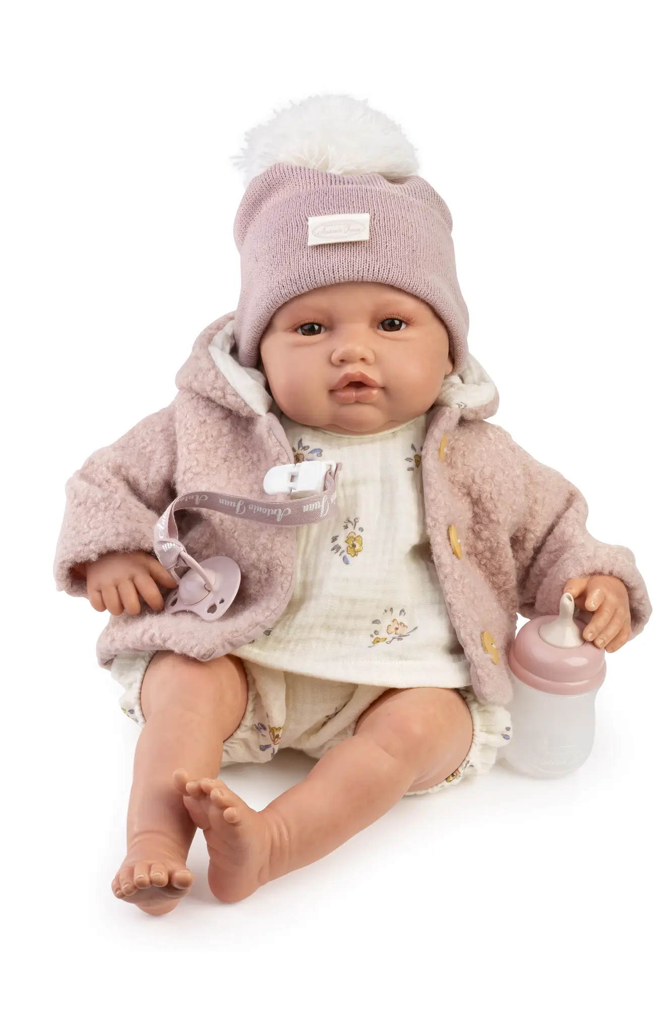 Reborn Baby Love Invierno con gorro y abrigo Muñeca Reborn Baby Love Invierno en primer plano, con gorro rosa de pompón, abrigo de pelo y vestido floral.